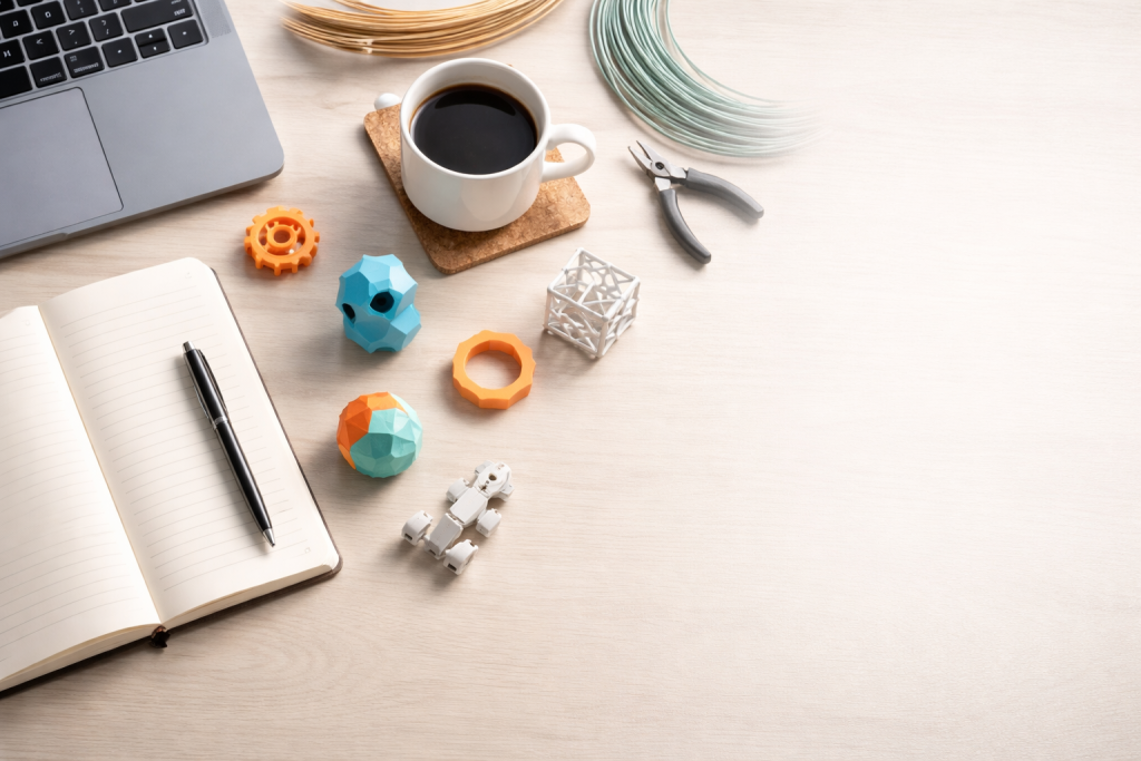 Standard blog-headerbillede, der viser et inspirerende skrivebordsmiljø med notesbog, laptop, 3D-printede modeller og plads til overskrift ovenpå billedet.